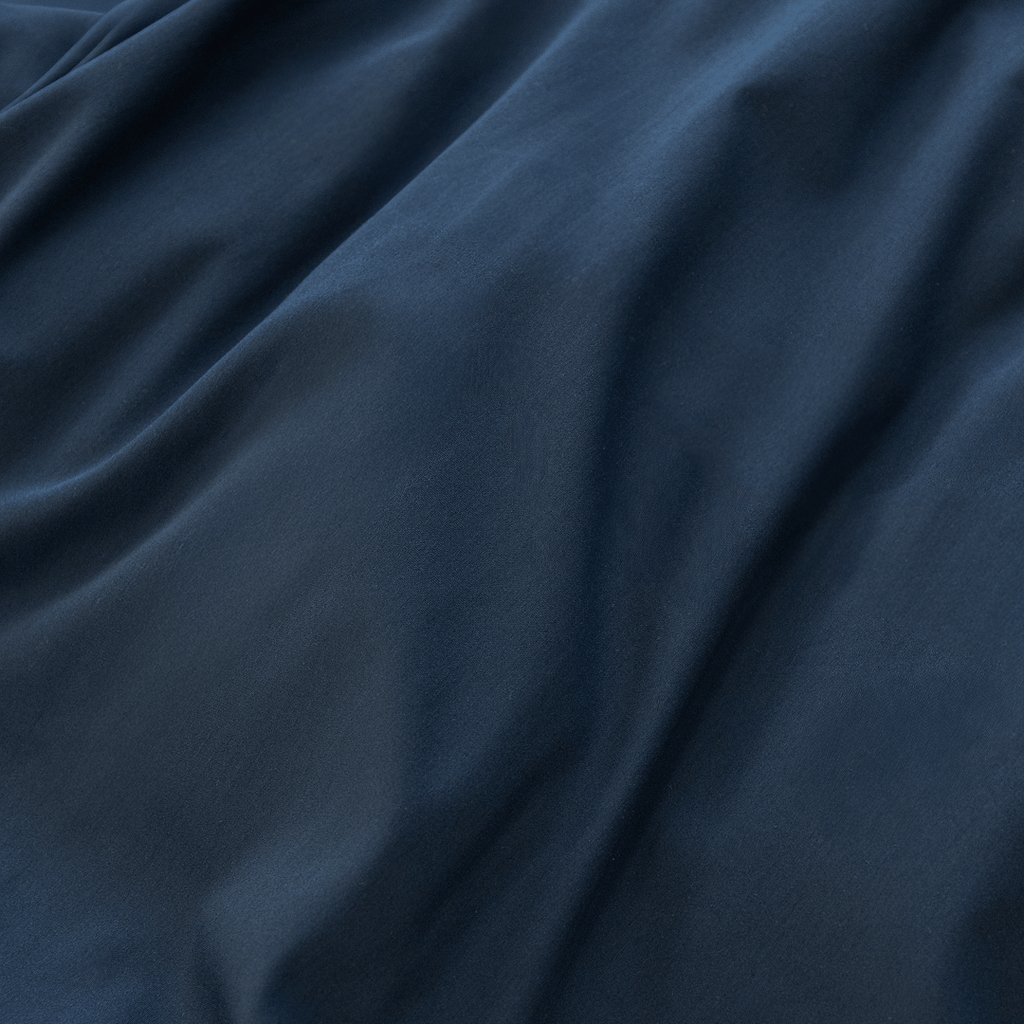 Extreme close-up showing the soft folds and smooth texture of navy blue cotton fabric