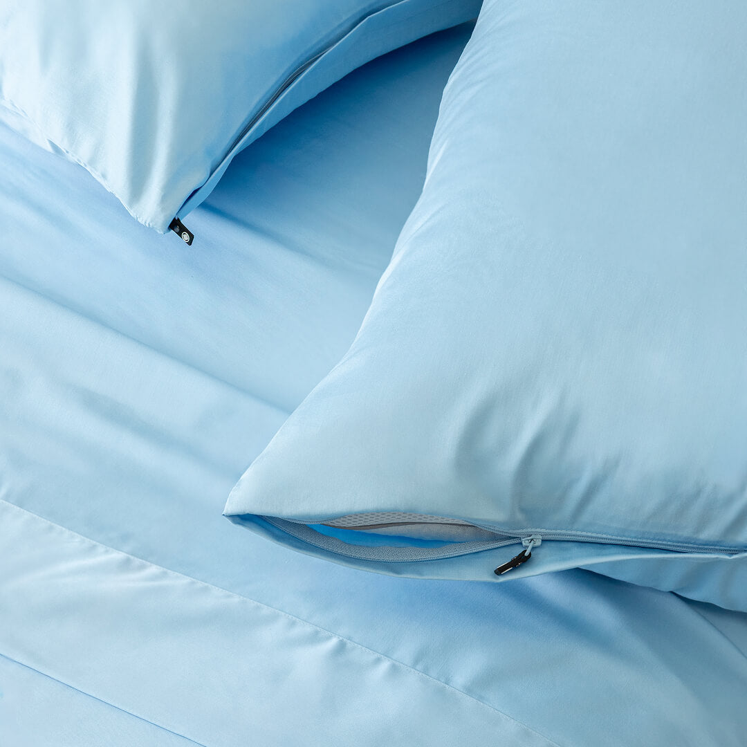 Pastel blue pillowcases on bedding, showcasing invisible zippers.
