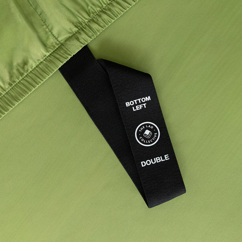 Close-up of a green fabric with a black label on a matching green background.