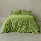 Green bedding set on a bed against a plain wall.