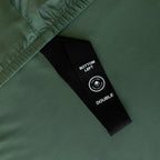 Close up of labelled corner loop strap on green fitted sheet.