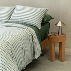 Stripe quilt cover paired with green sheets on bed.