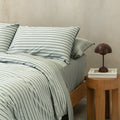 Stripe quilt cover on bed with bedside table, book and lamp.