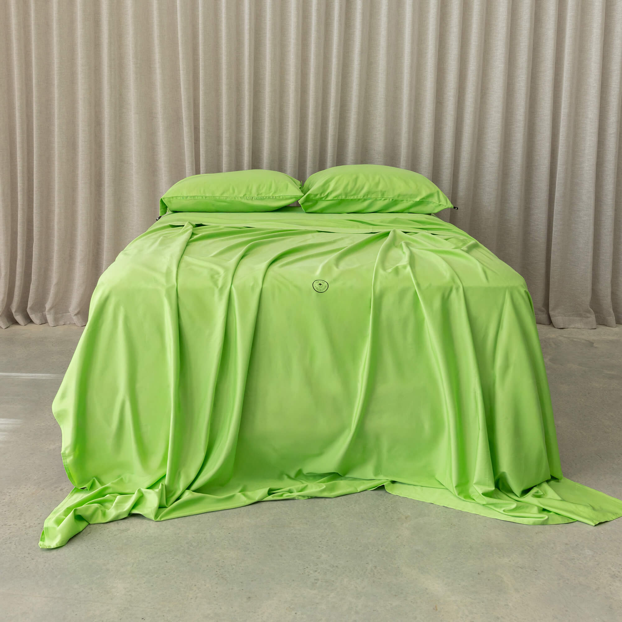 Lime green bedding set showcased on a bed, against a neutral background and a beige curtain. 