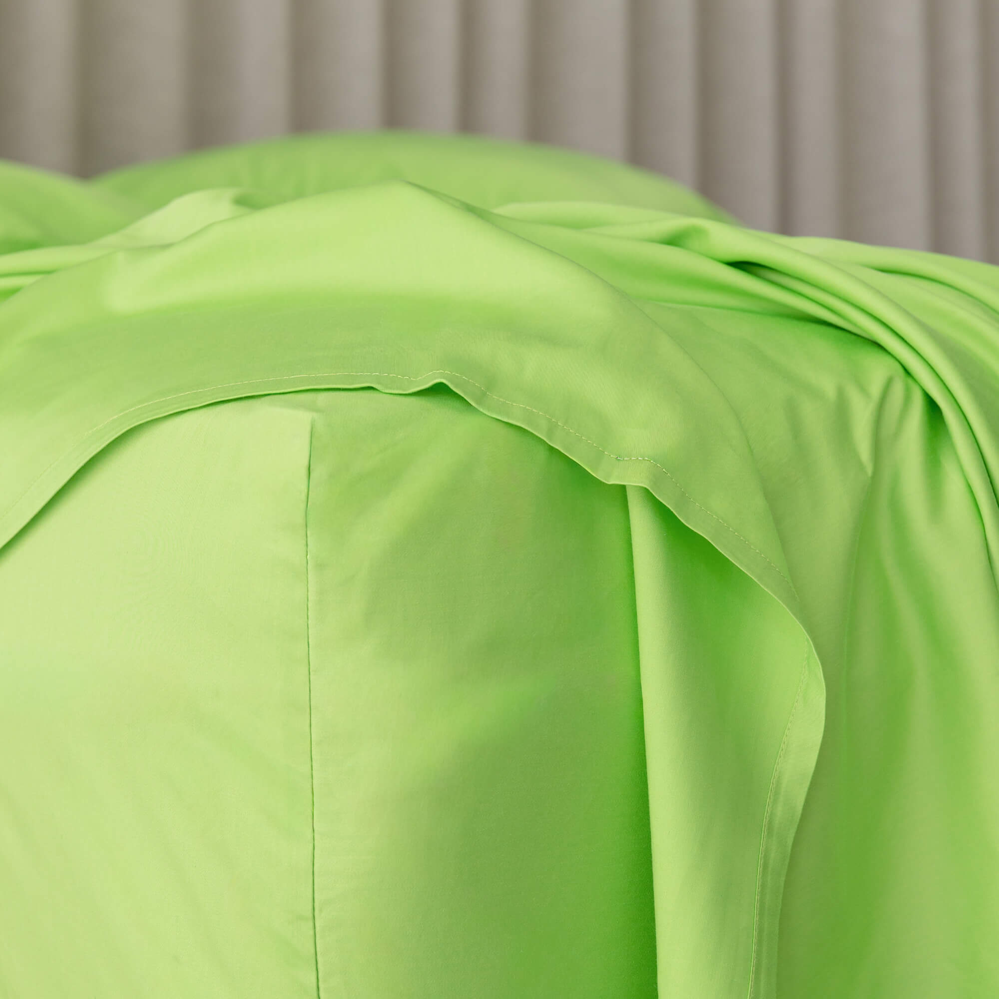 Close up of a lime green fitted sheet on the corner of the bed.