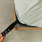 Light grey fitted sheet with labelled corner strap being pulled.