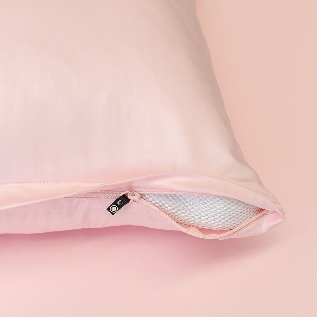 Close-up of a pink pillow with a zipper opening, showing the interior padding.