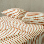 Striped bed sheets and pillows on a bed with a neutral background.