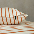 Striped pillow and duvet cover on a bed with a neutral background.