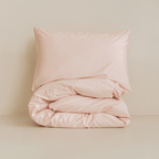 Folded blush pink quilt cover set with matching pillowcase, highlighting the soft fabric, premium finish, and minimalist presentation.