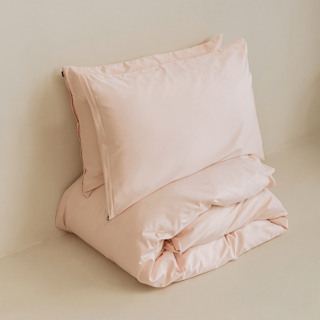 Folded blush pink quilt cover and pillowcase set styled for display, highlighting the soft-touch fabric, clean finish, and premium craftsmanship.
