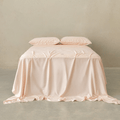 Soft blush pink fitted sheet set styled on a neatly made bed with matching pillowcases, featuring a smooth drape, elegant finish, and calming bedroom aesthetic.