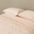 Close-up of blush pink fitted sheets and matching pillowcases, highlighting the soft-touch fabric, smooth texture, and refined appearance.
