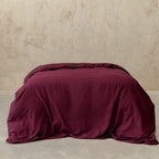 Maroon comforter on a bed against a beige wall
