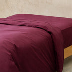 Maroon bedspread on a bed with a neutral background.