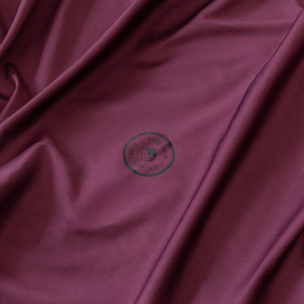 Close-up of burgundy fabric with a logo in the center.