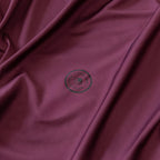 Close-up of burgundy fabric with a logo in the center.