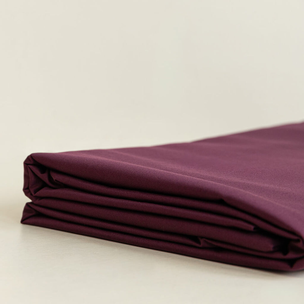 Folded burgundy fabric on a beige background.