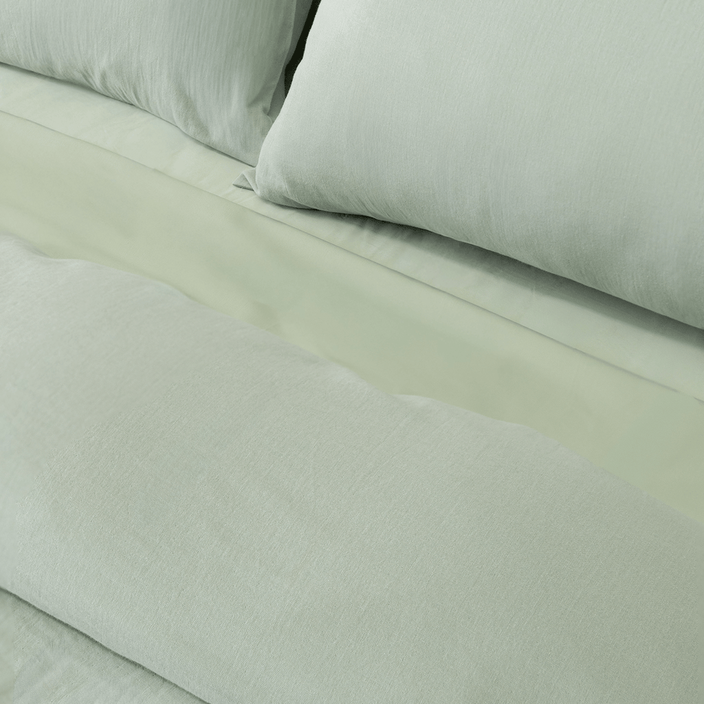 Close-up of matching sage green pillowcases and quilt cover, highlighting the soft washed fabric texture and coordinated bedding design.