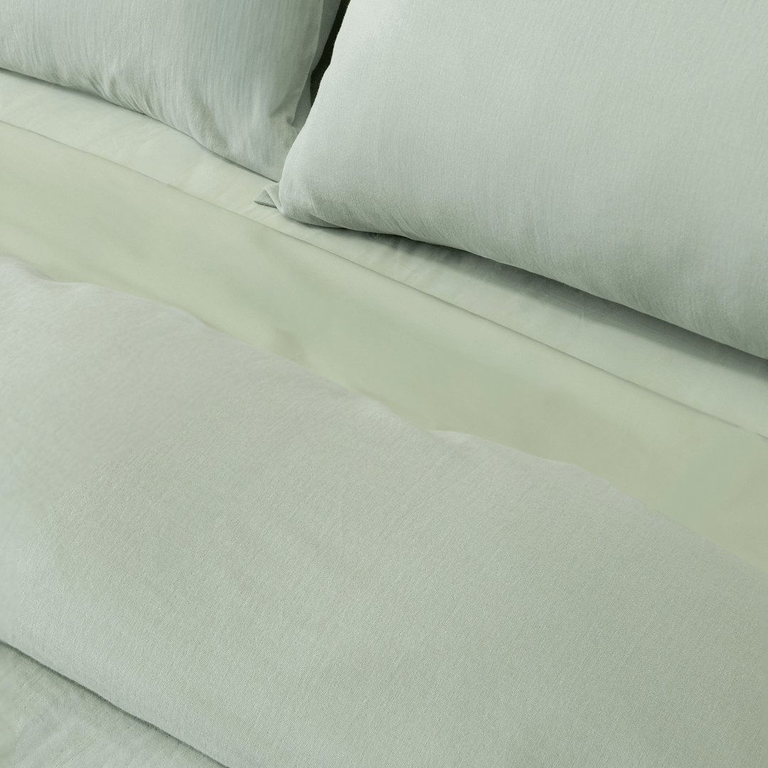 Close-up of matching sage green pillowcases and quilt cover, highlighting the soft washed fabric texture and coordinated bedding design.