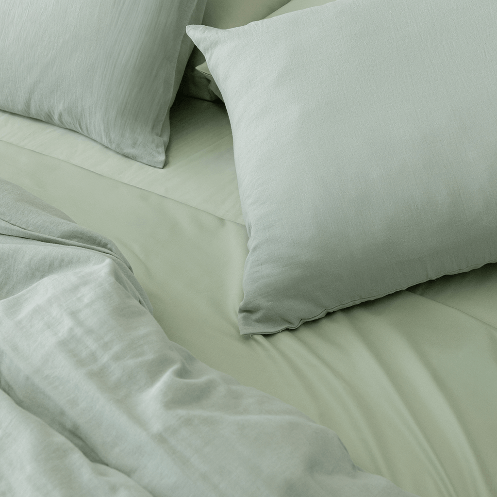 Styled bedroom scene featuring sage green bedding with matching pillowcases, highlighting the soft texture, relaxed appearance, and inviting comfort.