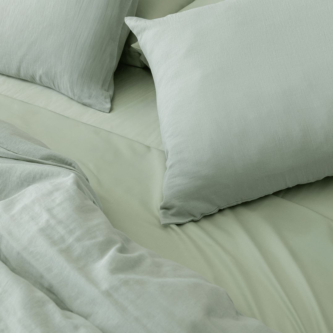 Styled bedroom scene featuring sage green bedding with matching pillowcases, highlighting the soft texture, relaxed appearance, and inviting comfort.