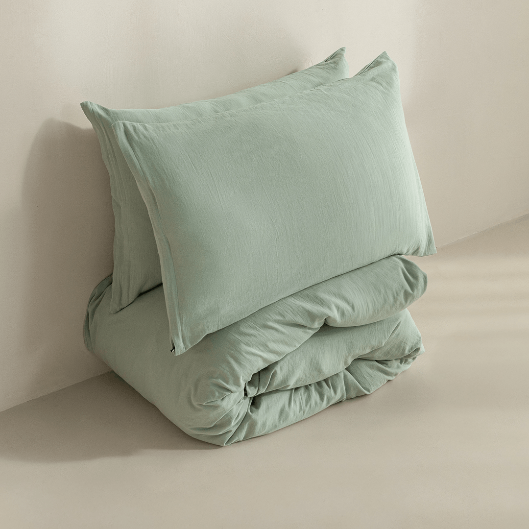 Folded sage green quilt cover set with matching pillowcases, highlighting the soft-touch fabric, casual drape, and minimalist presentation.