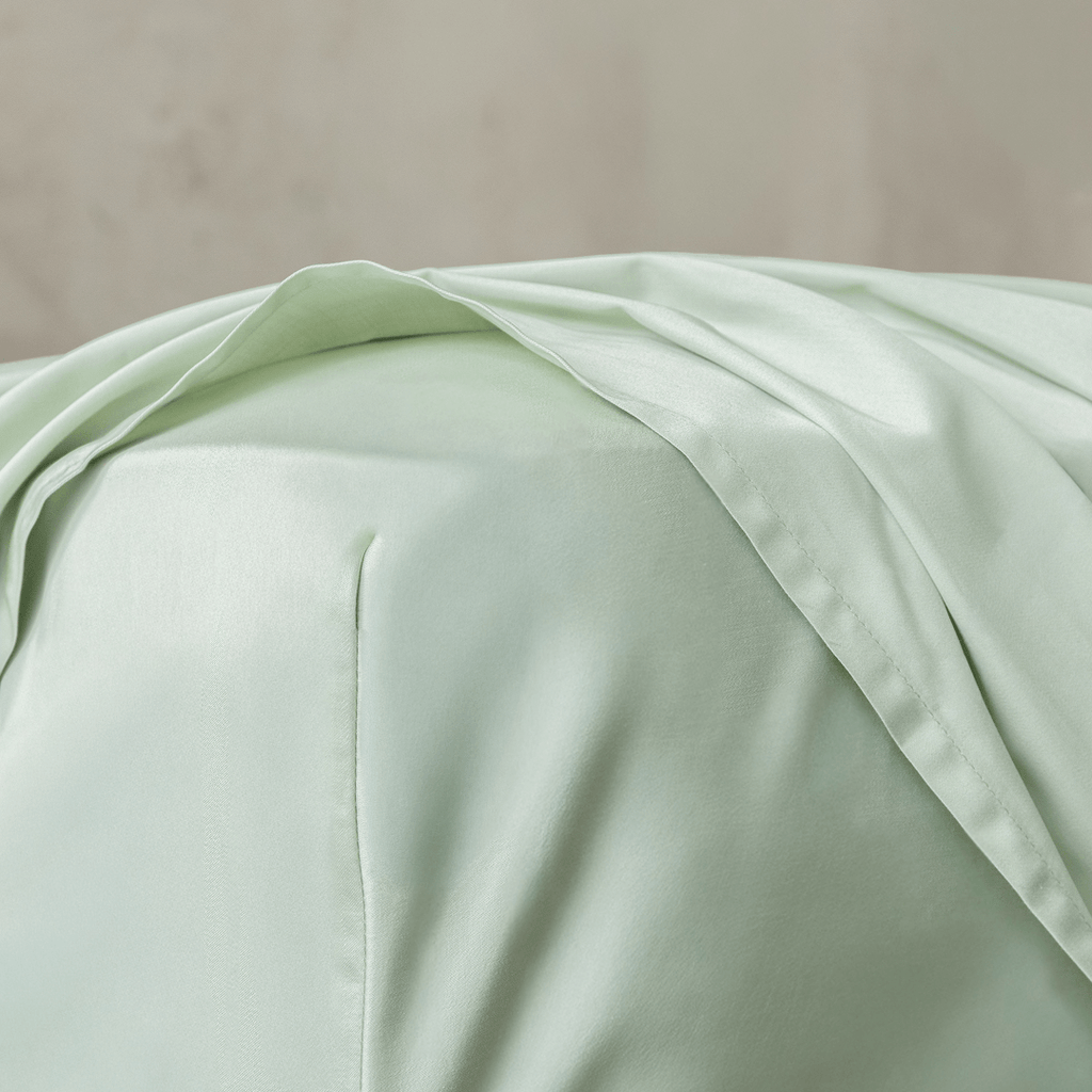 Close-up of the flat sheet draped over the mattress, highlighting the smooth bamboo cotton fabric, soft sheen, and lightweight feel.