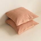 Two textured clay, European pillows stacked on a light beige surface.