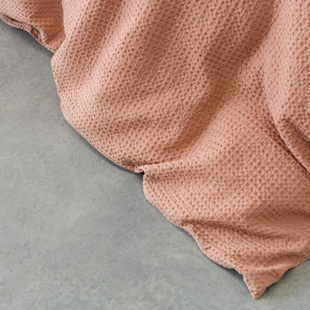 Warm clay coloured textured fabric on a grey surface.