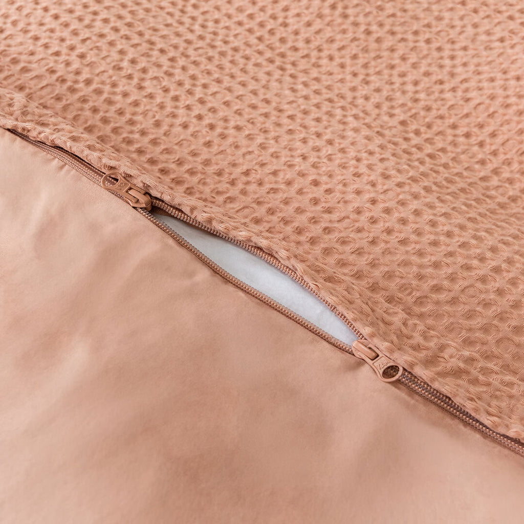 Close-up of a clay coloured, waffle textured fabric with a zipper.