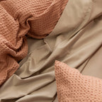 Close-up of beige and pink textured fabric with a pillow.