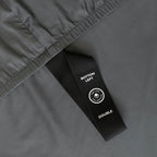 Close-up of a grey fabric with a black labelled loop strap on a matching grey background.