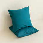 Two teal European pillowcases against a neutral background. 