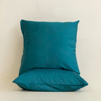 Two teal pillows on a beige background