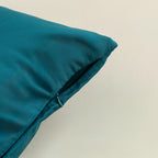 Teal pillow on a beige background, close up of zipper closure.