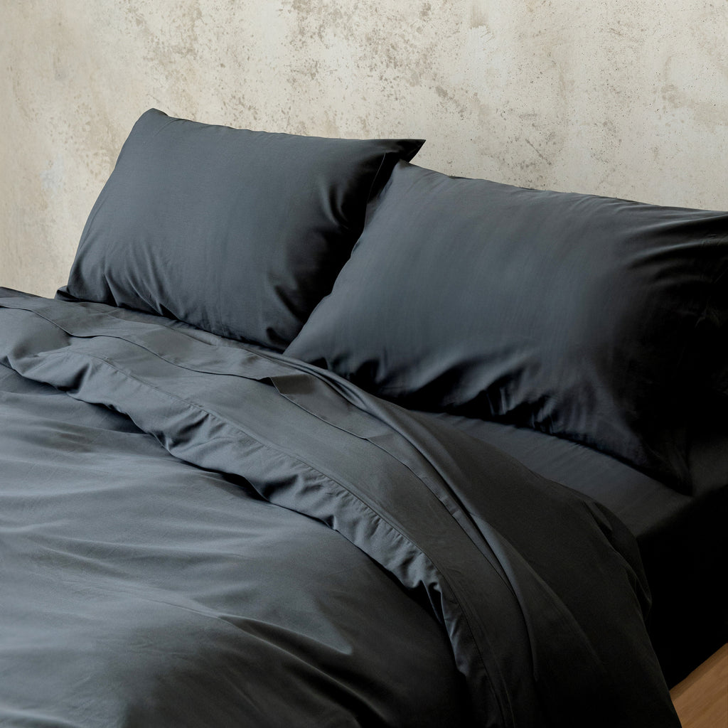 Black bedding set with pillows on a textured wall background