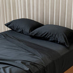 Black bedspread with pillows on curtain wall