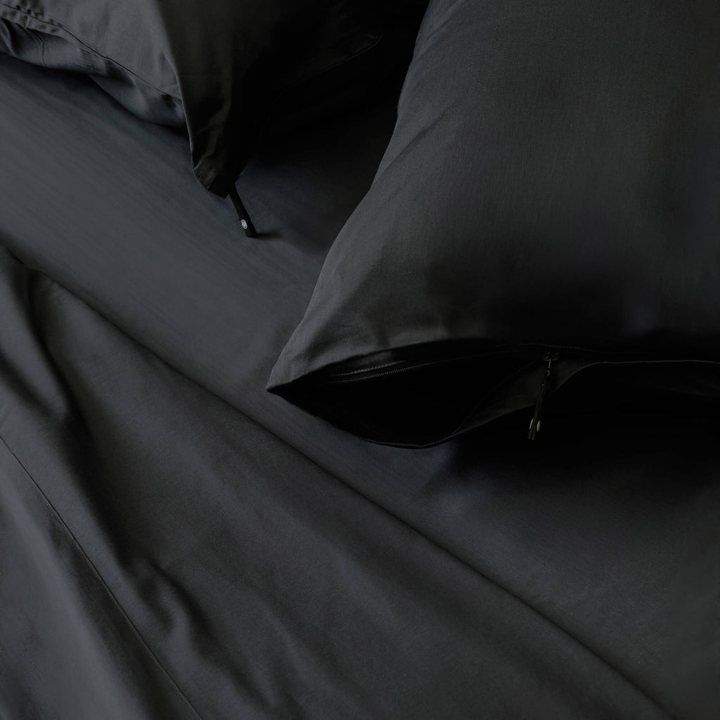 Close-up of black bedding with a pillow on a bed.