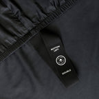 Close up of Black bed sheets with corner strap on a bed with a neutral background