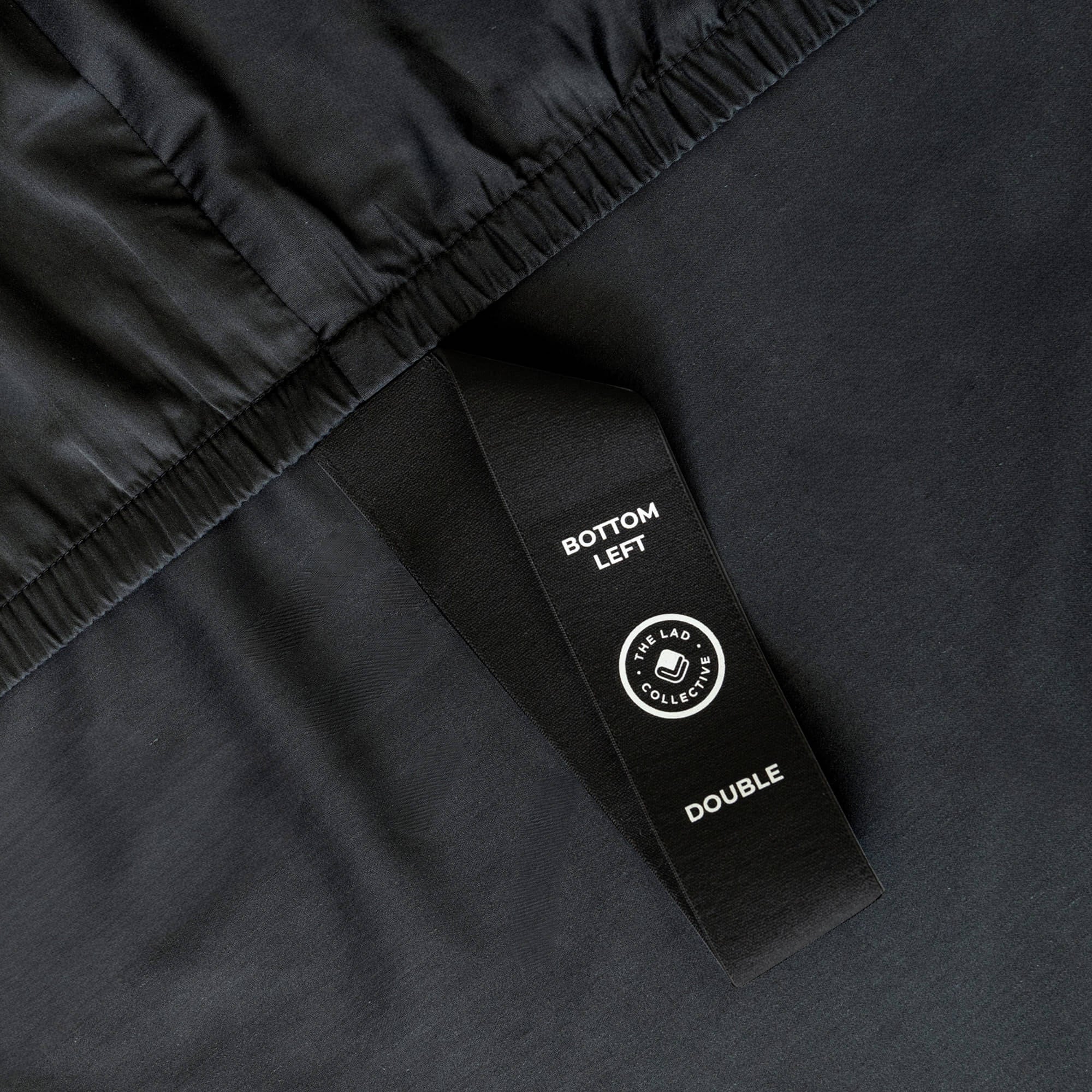 Close up of corner strap detail in dark charcoal fitted bed sheet