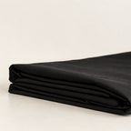 Folded black fabric on a light beige background.