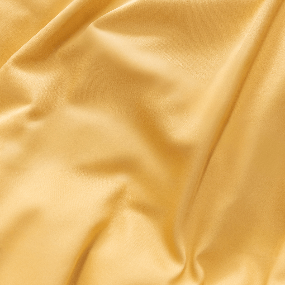 Extreme close-up showing the soft drape and silky sheen of golden yellow fabric
