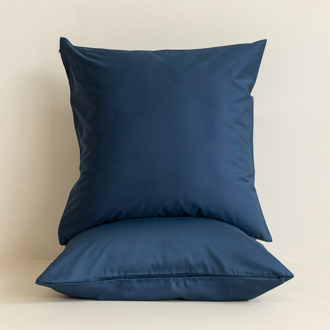Two navy blue pillows on a beige background