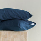 Two navy blue pillows stacked on a beige surface with a neutral background.