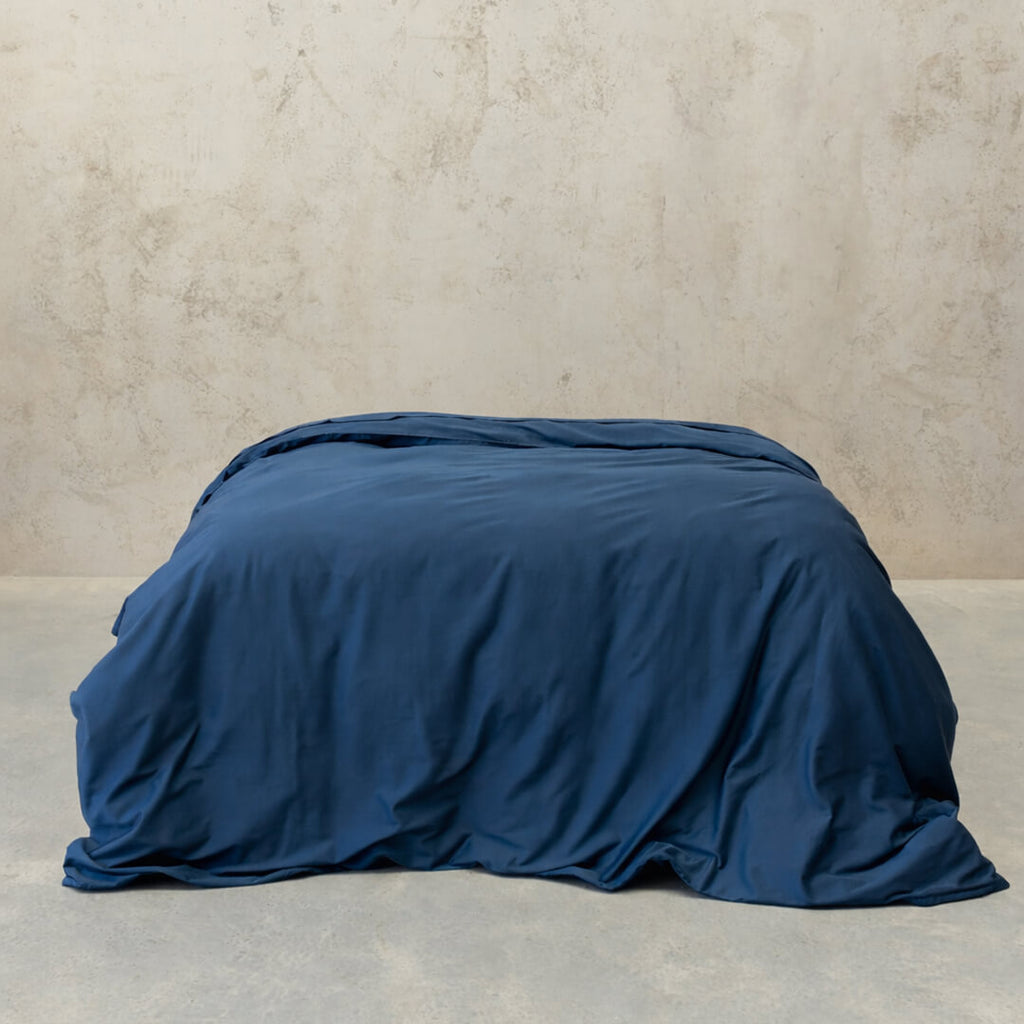 Navy blue quilt cover on bed, with neutral background. 