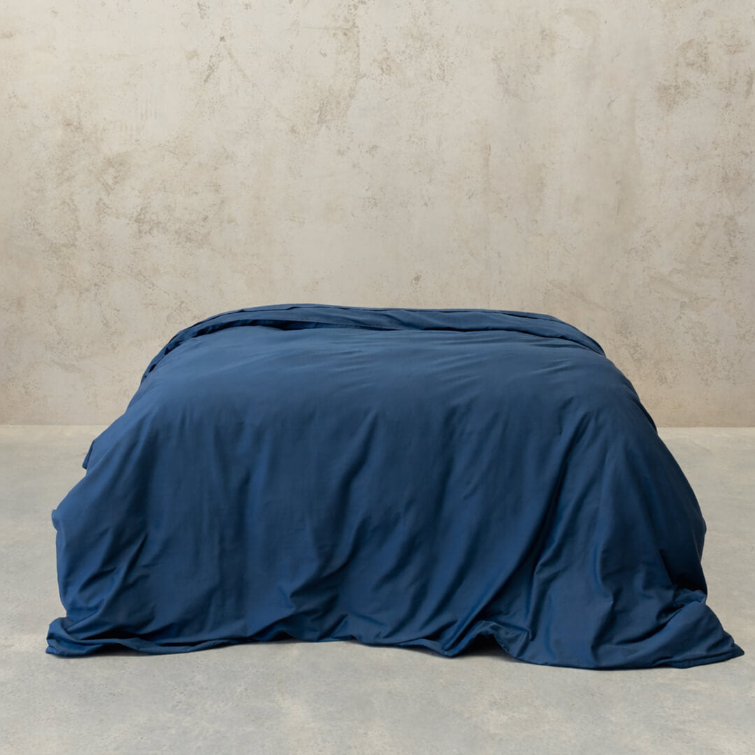 Navy blue quilt cover on bed, with neutral background. 