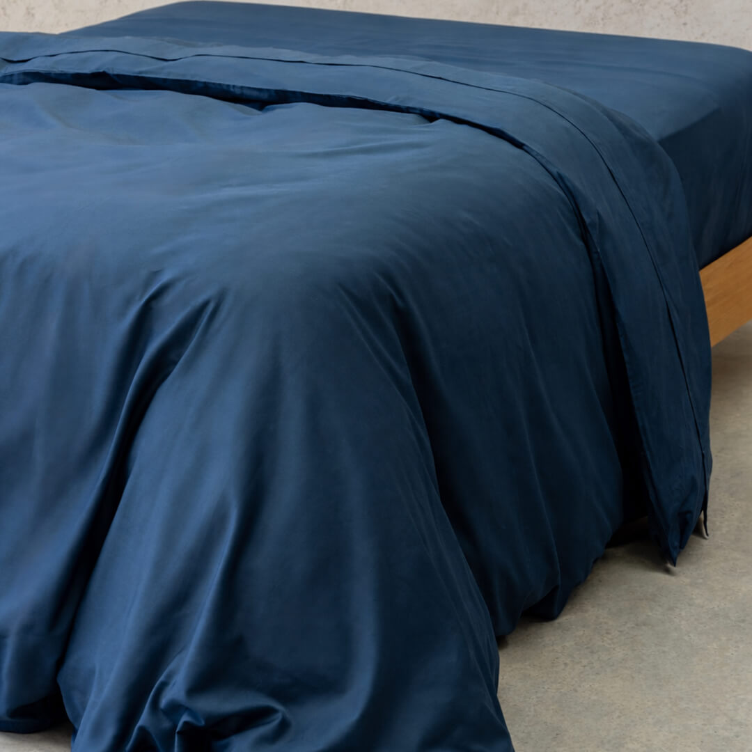 Navy blue quilt cover on bed, with neutral background. 