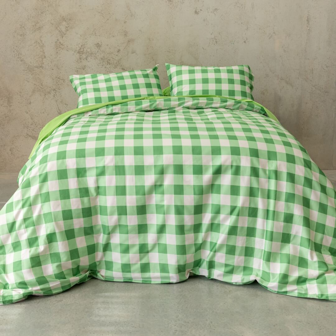 Meadow green gingham print quilt cover set on a bed, against a neutral concrete look backdrop.