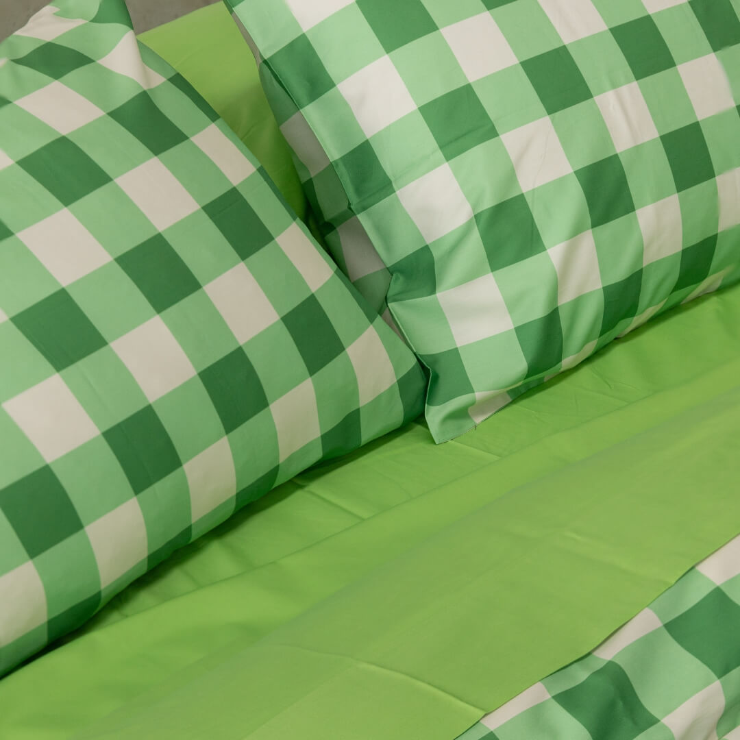 Meadow green gingham print quilt cover set on a bed. Close up of the pillowcases against a contrasting green sheet set.